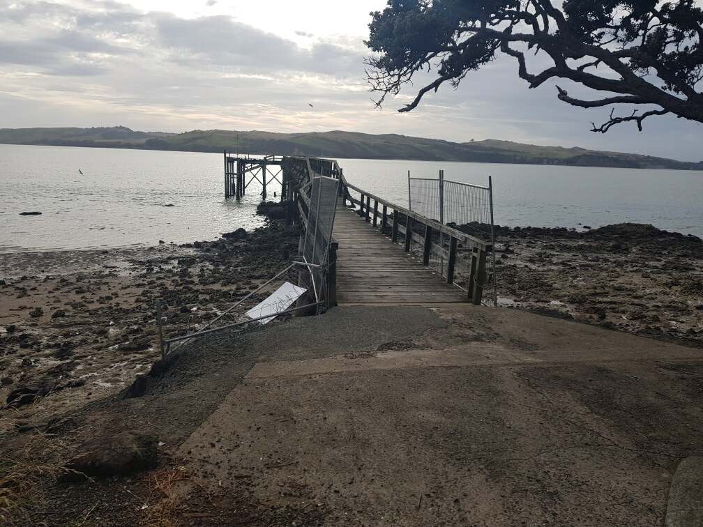 Wharf over the water with damaged fencing at entrance.